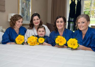 smiling bride & bridesmaids with yellow flower bouquets in dressing gowns