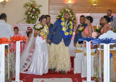 Colourful and happy Tokelauan bride and groom walking down aisle in church