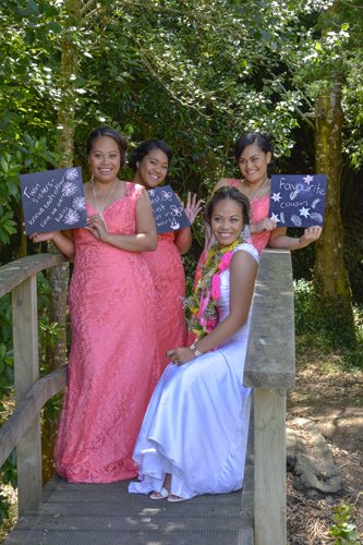 Colourful Tokelauan wedding bride and bridesmaids on rustic bridge with blackboards