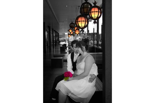Black & white image of bride & groom seated outdoors on Wellington waterfront with yellow lights