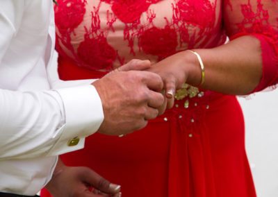 Brightly dressed bride & groom exchanging rings