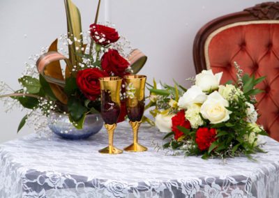 Beautiful registry table setting of bouquets, gold & red goblets and antique red chair