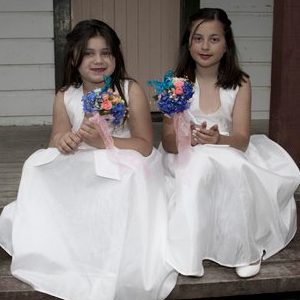 2 cute flower girls sitting on steps & holding bouquets