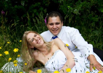bride & groom laughing and relaxing in long grass and dandelion flowers