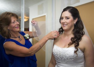 Bride's mum adjusting smiling bride's veil, before Pencarrow Lodge wedding