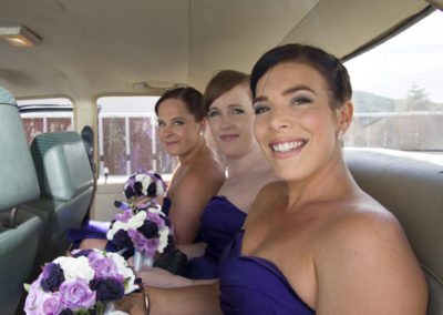 smiling bridesmaids in back of classic car on way to Pencarrow Lodge wedding