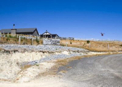 Pencarrow Lodge viewed from road below, with groomsmen helicopter landing under a bright blue sky