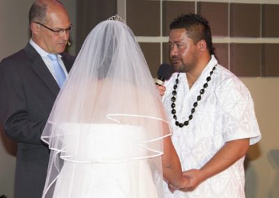 Samoan couple, holding hands, while celebrant holds microphone for groom to say vows