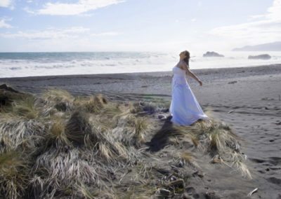 Pencarrow Lodge wedding bride spinning on beach as wind blows tussock grass wildly