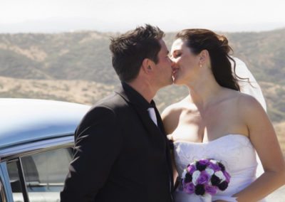 Pencarrow Lodge wedding closeup of happy bride & groom kissing by classic car