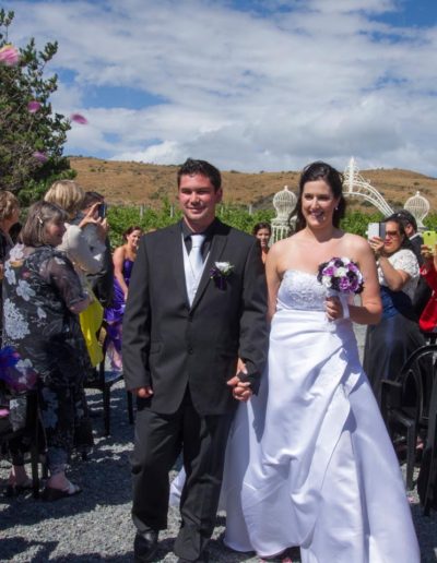 Pencarrow Lodge wedding smiling bride & groom walk hand in hand down aisle as guests take photos