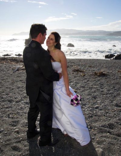 Pencarrow Lodge wedding bride & groom embrace on windy beach