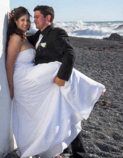 Pencarrow Lodge wedding saucy bride & groom with leg raised leaning against lighthouse