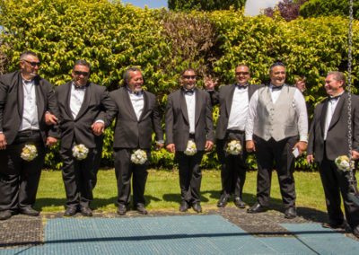 Maori groom & groomsmen larking around with bouquets between their knees