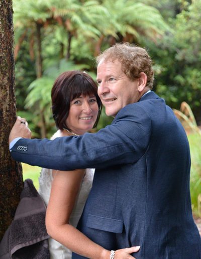 bride & groom in native bush setting embracing while leaning against tree