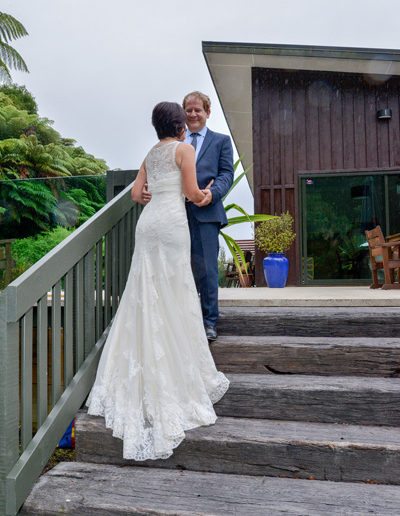 bride & groom romantically embracing on outdoor stairs, good view of gown train