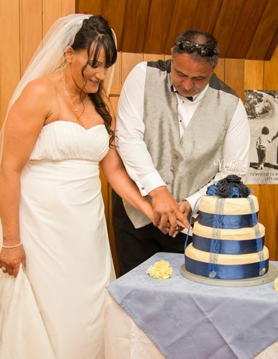 Maori bride & groom smiling as they cut multi-layered wedding cake