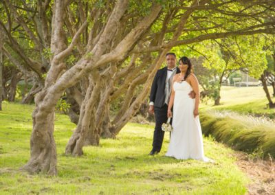 Maori bride & groom embrace beside gnarled trunk trees Waiwhetu stream