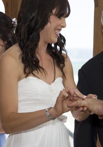 bride laughing as she tries to get grooms ring on finger closeup