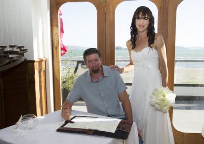 bride & groom with groom signing register, Petone beach in background