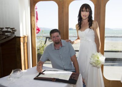 bride & groom with groom signing register, Petone beach in background