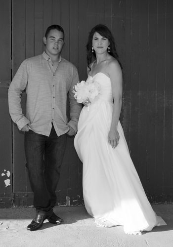 B&W bride with handsome brother by wooden wall