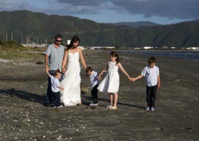bride & groom & children walking hand in hand on beach