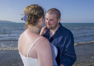 closeup of bride's hairpiece as couple embrace on beach