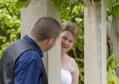 happy bride & groom peeking at each other around concrete column