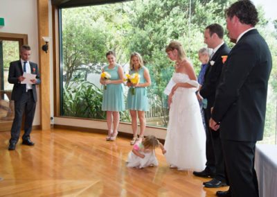 little girl peeking up bride's gown, beautiful bushy setting