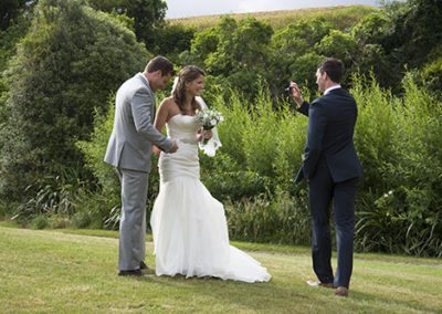 groom's bother taking a photo of bride & groom in lovely nature setting