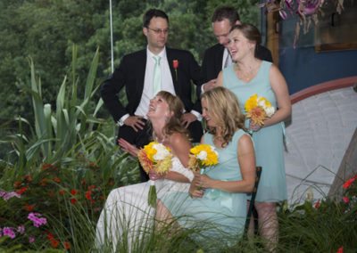 laughing wedding party amidst greenery & dinghy behind