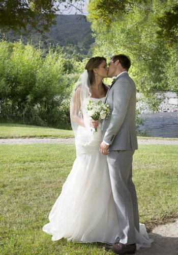 bride & groom's first kiss in lovely rural setting with river behind