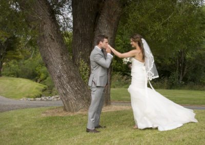 groom romantically kissing bride's hand in country setting