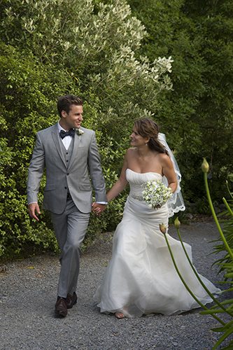 Relaxed bride & groom holding hands as they walk up country path