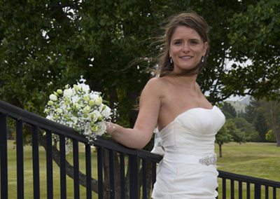 Closeup of windswept sexy bride leaning against fence