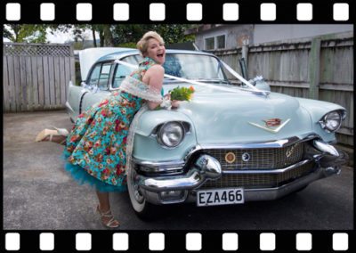 colourful bridesmaid leaning over classic car