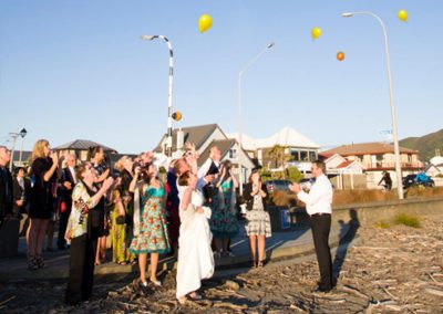 wedding guests & bridal couple releasing balloons on Petone beach