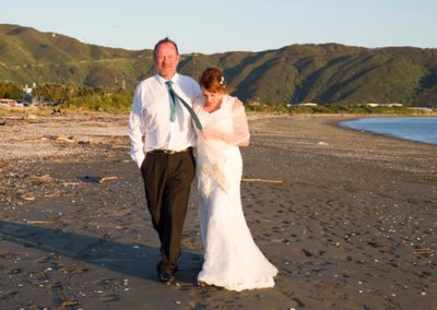 bride & groom walking arm in arm along Petone beach