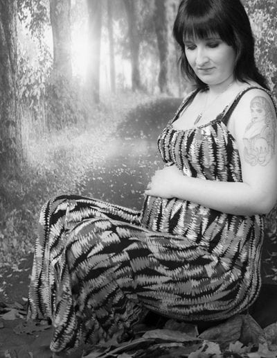 pregnant lady in patterned dress seated in front of autumn trees black & white
