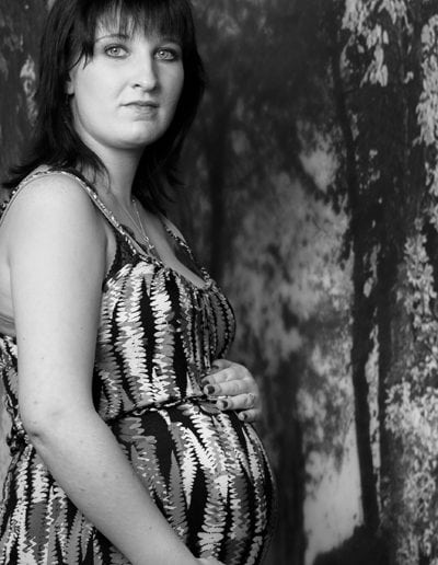 pregnant lady in patterned dress standing in front of autumn trees black & white