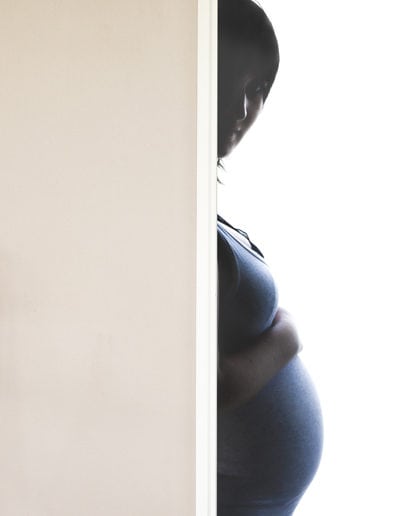 pregnancy maternitypregnant woman's head & belly poking out from behind door