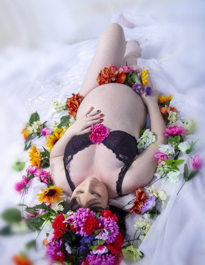pregnant lady lying on her back, bare belly, surrounded by pink flowers