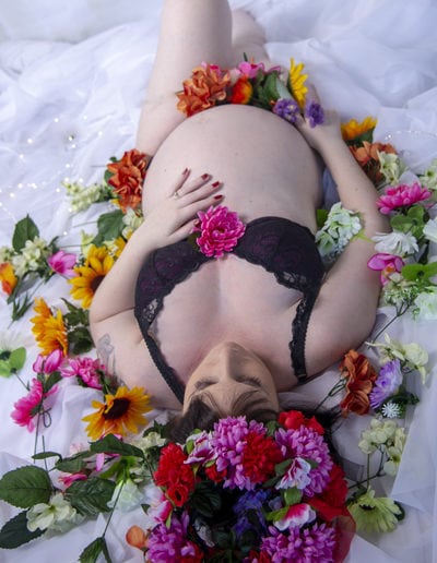 pregnant lady lying on her back, bare belly, surrounded by pink flowers