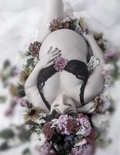 pregnant lady lying on her back, bare belly, surrounded by pink flowers