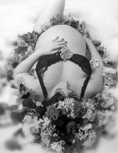 pregnant lady lying on her back, bare belly, surrounded by flowers black & white
