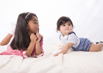 cute brother & sister sitting on rug looking off to one side