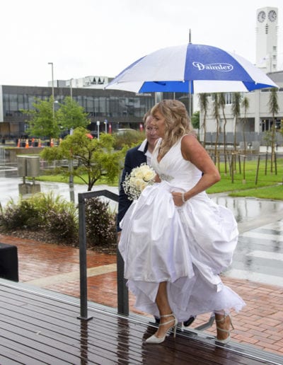 Bride walking up steps in rain