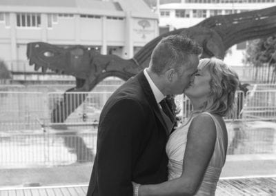 Dowse Art Gallery Bride & groom kissing in front of T rex